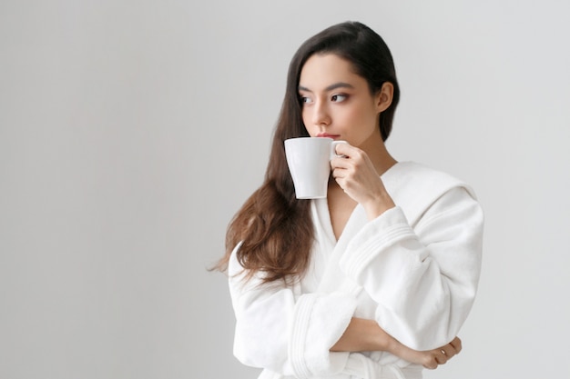 Fille avec une tasse blanche dans les mains. Portrait de femme décontractée avec boisson thé ou café femme indors home. Prise de vue en studio.