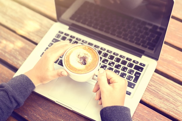 Fille avec une tasse de café et un ordinateur portable le matin