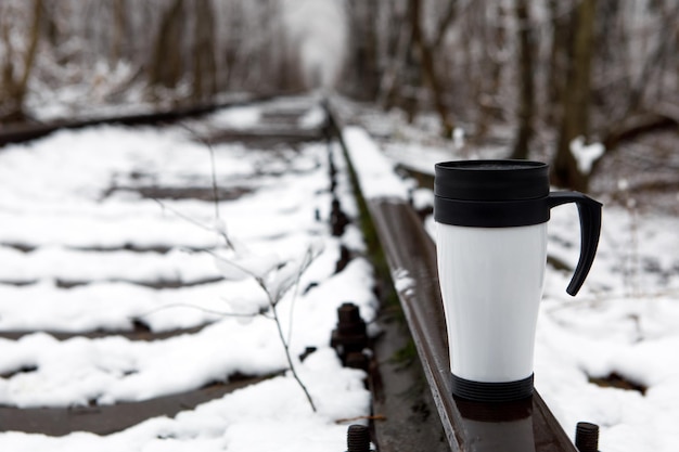 Fille avec une tasse thermos en hiver