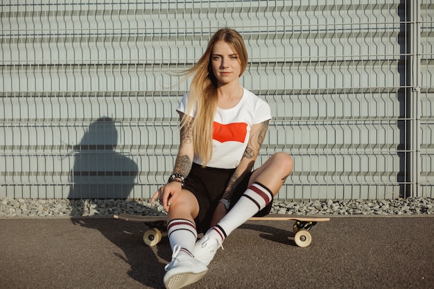 Fille avec des tatouages équitation longboard dans la ville