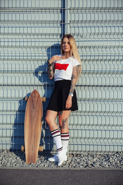 Fille avec des tatouages équitation longboard dans la ville