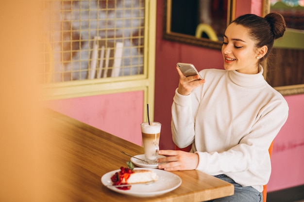 Fille avec téléphone, boire du café dans un café