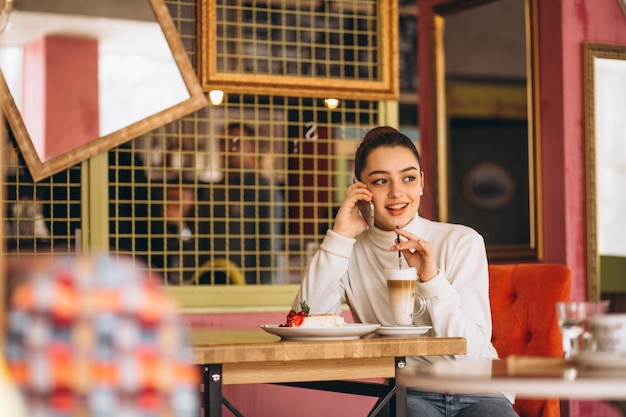 Fille avec téléphone, boire du café dans un café