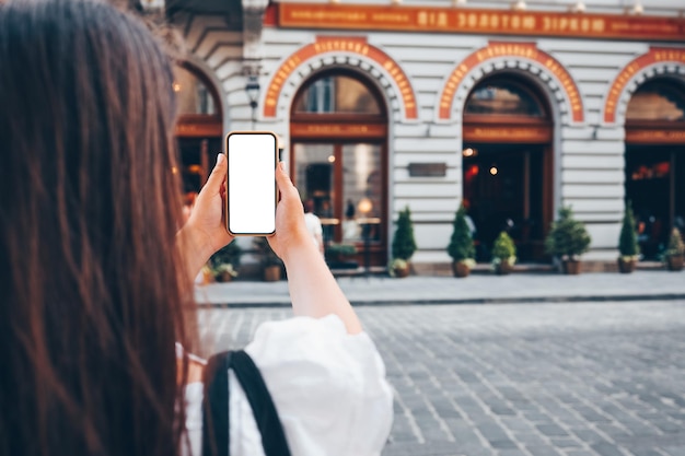 Une fille avec un téléphone dans les mains avec un écran isolé sur le fond de la façade du magasin Place pour votre publicité