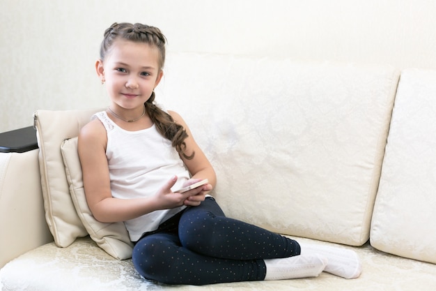 Une fille avec un téléphone portable sur le canapé.