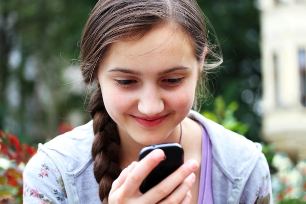 La fille avec un téléphone portable lit le message