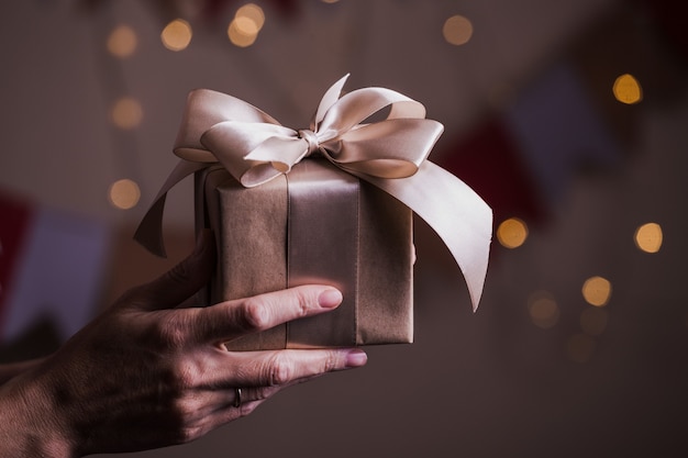 Fille tenant un beau cadeau pour Noël. boîte et arc et bokeh en arrière-plan