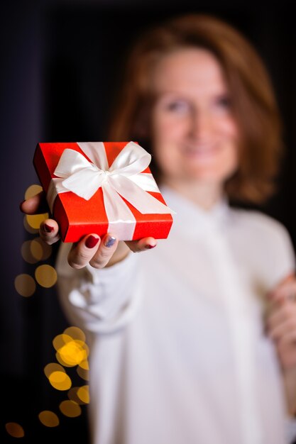 Fille tenant un beau cadeau pour la Saint Valentin. boîte rouge et arc blanc et bokeh en arrière-plan