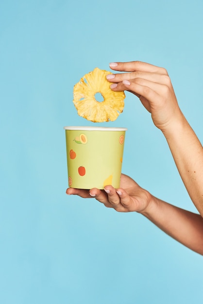 Fille tenant une boîte en papier avec des chips d'ananas.