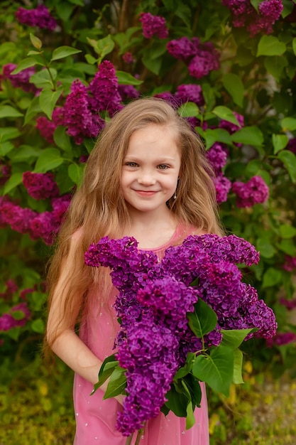 Une fille tenant un bouquet de fleurs de lilas violet