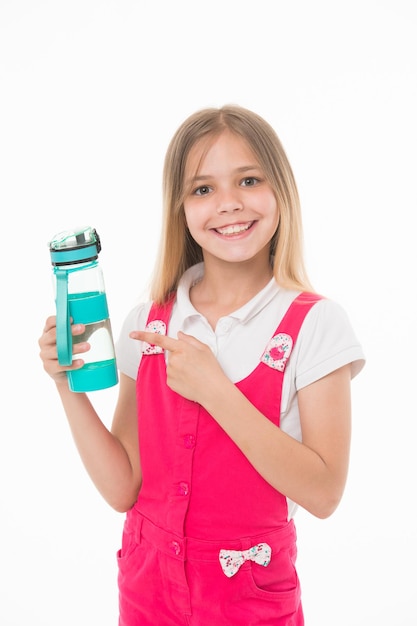 Fille tenant une bouteille d'eau Enfant avec un grand sourire portant une combinaison de saut rose Joli enfant isolé