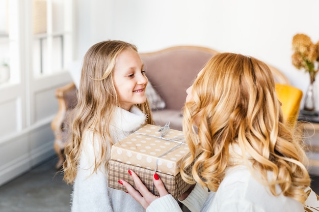 fille tenant un cadeau et le donne à sa mère