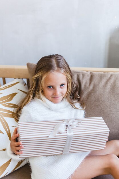 Fille tenant un cadeau, l'intérieur est décoré pour Noël