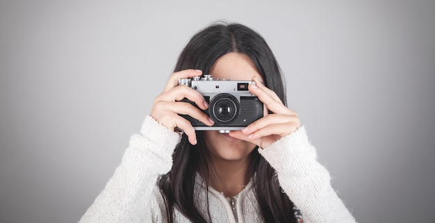 Fille tenant une caméra rétro au bureau.