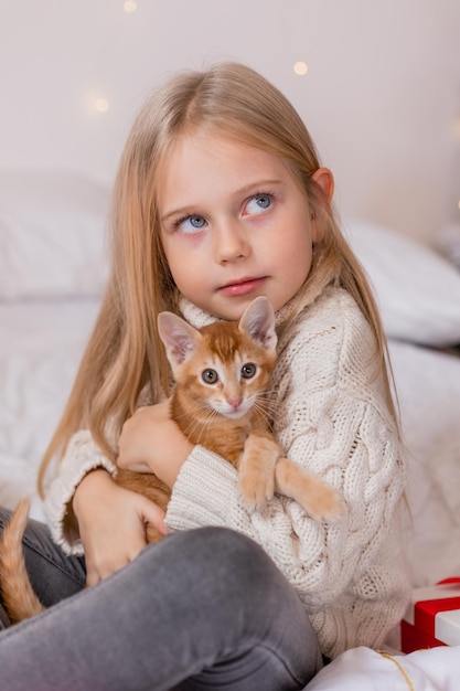 Une fille tenant un chat sur un lit