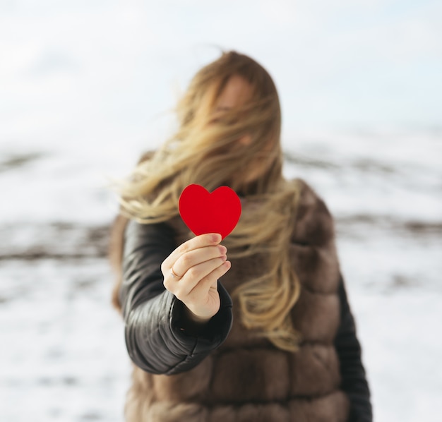 Une fille tenant un coeur rouge dans sa main.