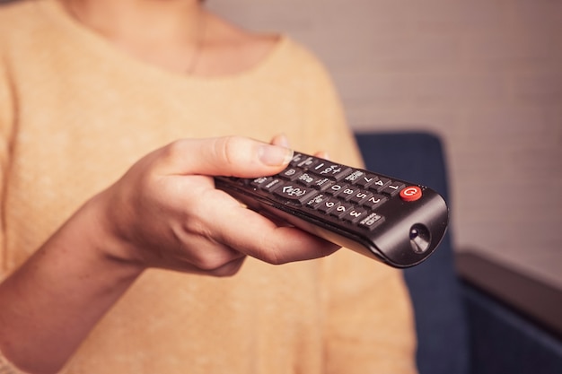 une fille tenant dans ses mains une télécommande du téléviseur