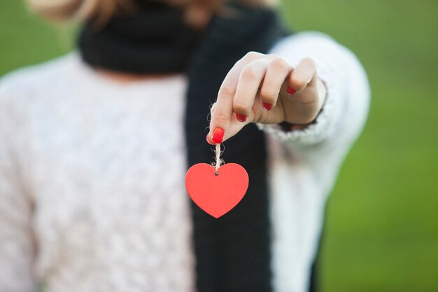 Fille tenant une décoration coeur en papier.