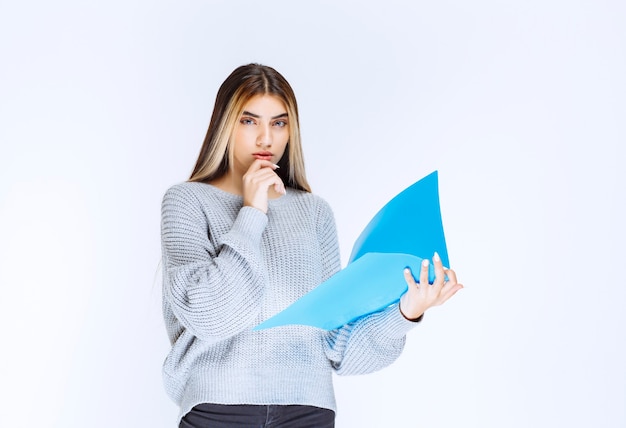 Fille tenant un dossier de rapport bleu et pensant.