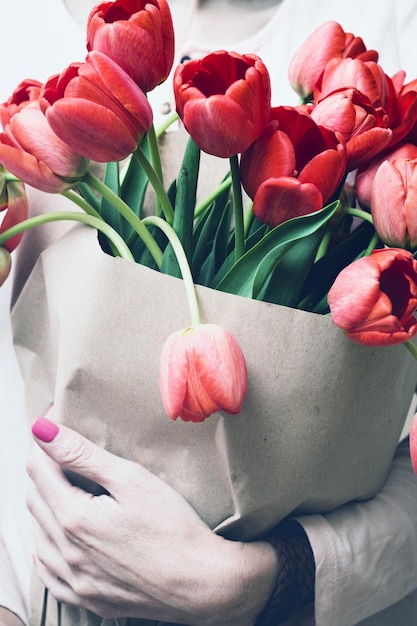 Photo fille tenant un énorme bouquet de tulipes rouges dans leurs mains printemps lumineux