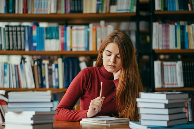 Une fille tenant une étagère à livres Photo de haute qualité Étudiant dans la bibliothèque