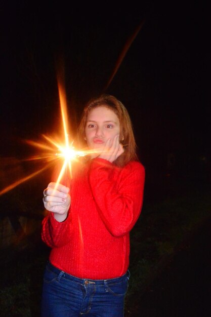 Photo fille tenant une étincelle éclairée alors qu'elle se tient sur la terre la nuit