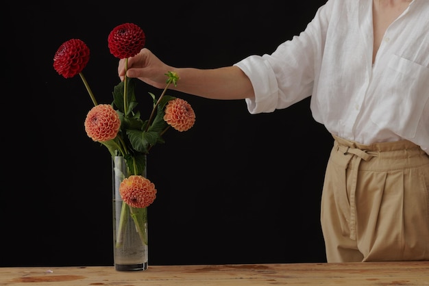 Fille tenant une fleur de dahlia dans un vase en verre sur une maquette de fond sombre de table en bois