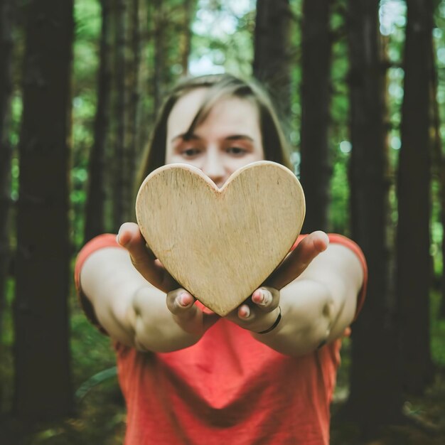 Une fille tenant une forme de cœur en bois Concept pour donner de l'amour