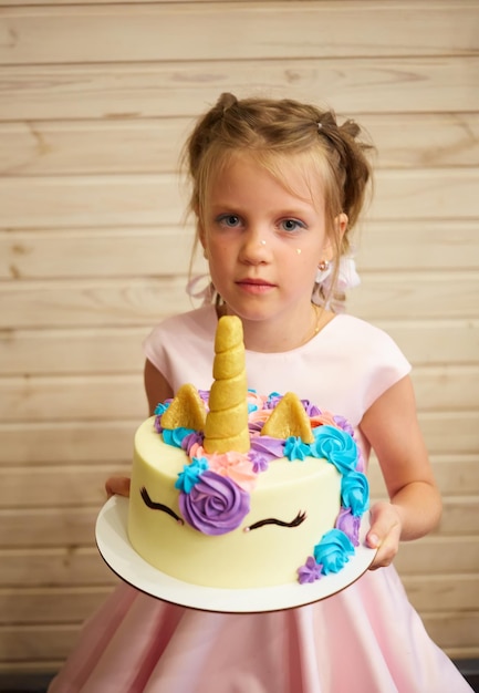 Fille tenant un gâteau sous forme de licorne