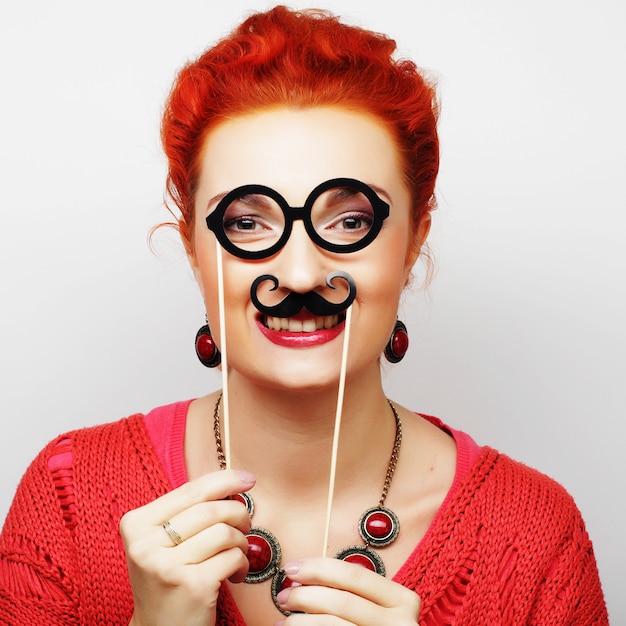 Fille tenant une moustache et des lunettes sur un bâton.