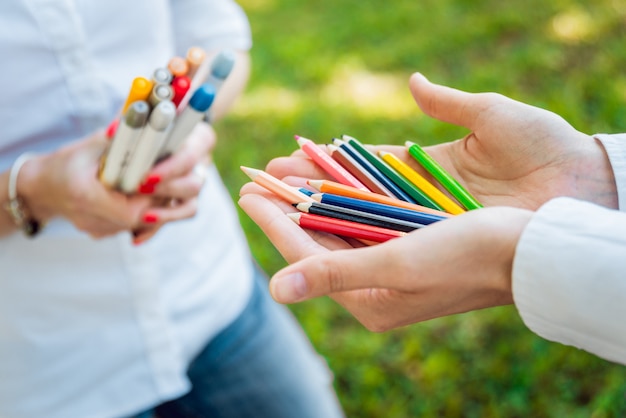 Fille tenant de nombreux crayons en bois colorés dans les mains.