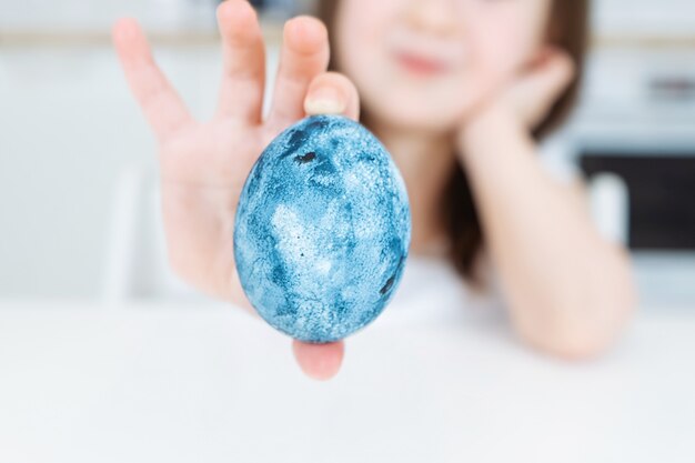 Fille tenant un oeuf de Pâques bleu dans ses mains. Gros plan, festif, oeuf Oeufs à colorier de l'espace