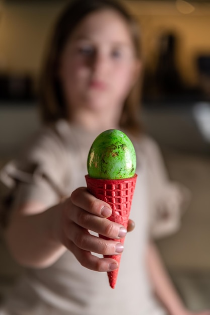 Fille tenant un oeuf de Pâques dans un cornet de crème glacée coloré