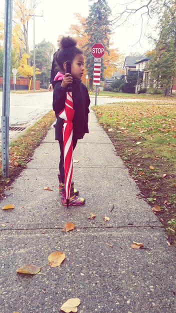 Photo une fille tenant un parapluie sur le trottoir.