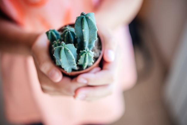 Une fille tenant un petit cactus en pot avec un arrière-plan défocalisé