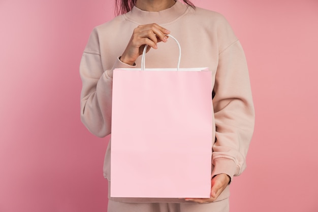 Fille tenant un sac en papier rose.