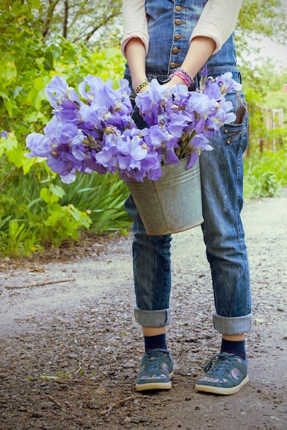 Fille tenant un seau dans le jardin avec des iris