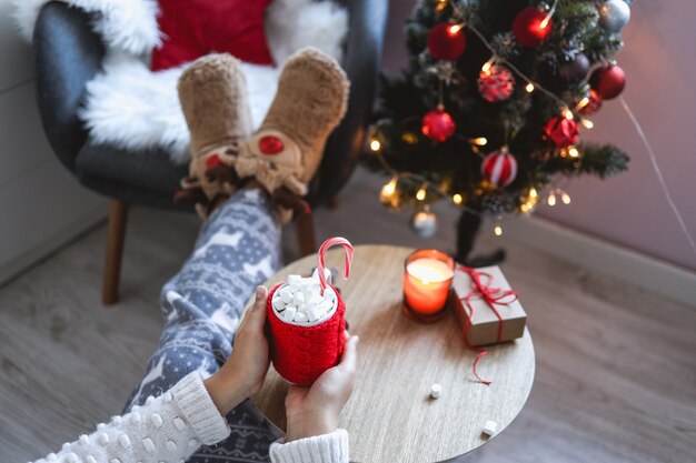 Fille tenant une tasse rouge avec du cacao et des guimauves dans ses mains, confortable matin de Noël