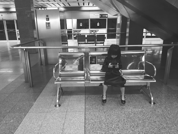 Photo une fille tenant un téléphone portable sur un siège à la gare