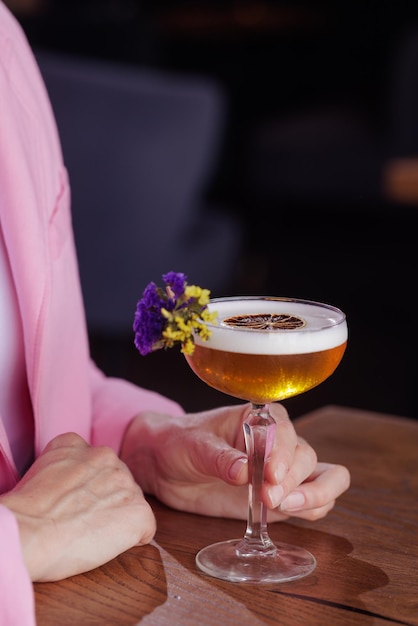 Fille tenant un verre avec un cocktail dans un café ou un restaurant concept de restaurant agrandi