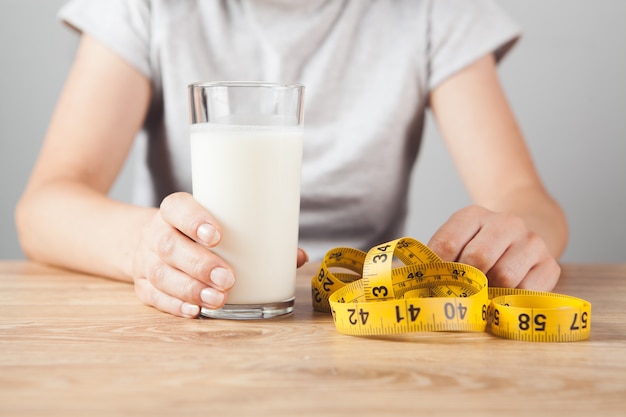 Fille tenant un verre de lait et un ruban à mesurer