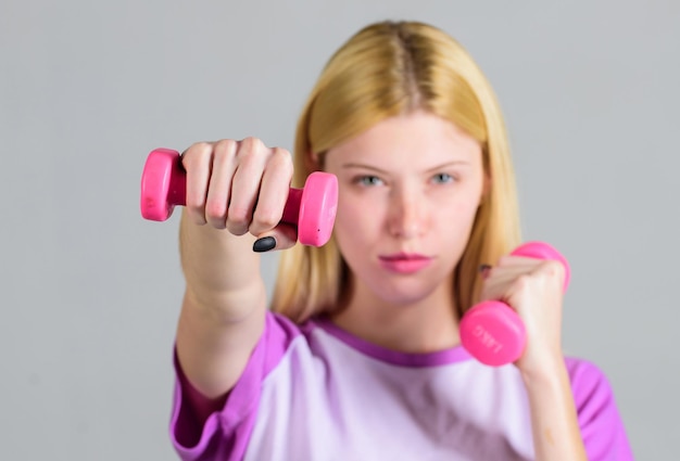 Fille tenir des haltères. Exercices de biceps pour femme. Instructeur de conditionnement physique. Concept de mode de vie sain. Entraîneur de fitness femme exerçant avec des haltères. Exercices faciles avec des haltères. Entraînement avec des haltères.