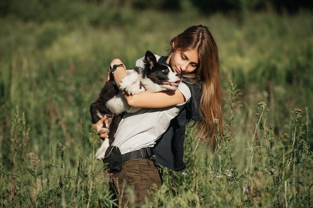 Fille tenir sur ses mains chiot border collie noir et blanc dans le domaine