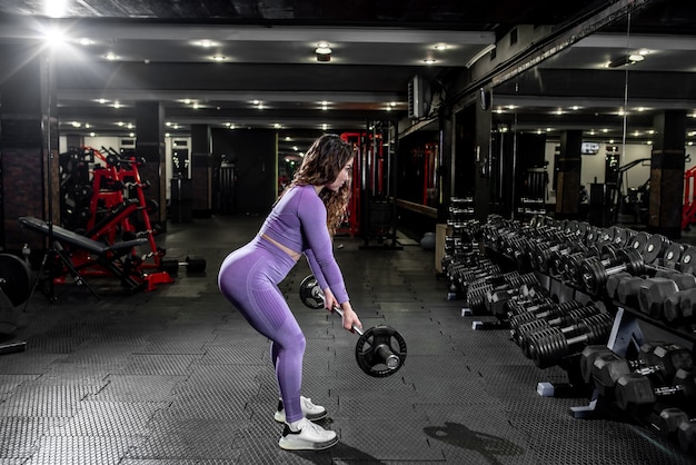 Une fille en tenue de sport dans une salle de sport professionnelle fonctionne avec des équipements de fitness.