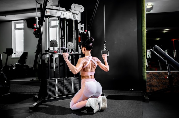 Une fille en tenue de sport dans une salle de sport professionnelle fonctionne avec des équipements de fitness.