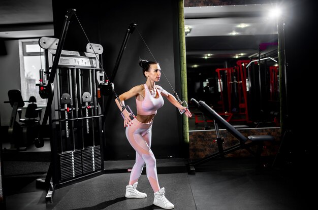 Une fille en tenue de sport dans une salle de sport professionnelle fonctionne avec des équipements de fitness.