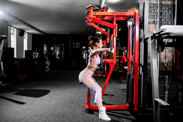 Une fille en tenue de sport dans une salle de sport professionnelle fonctionne avec des équipements de fitness