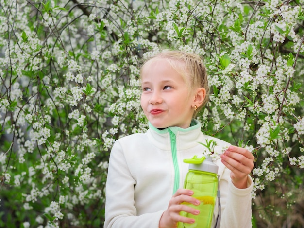 Fille en tenue de sport tenant une bouteille de boisson rafraîchissante en fleurs de cerisier