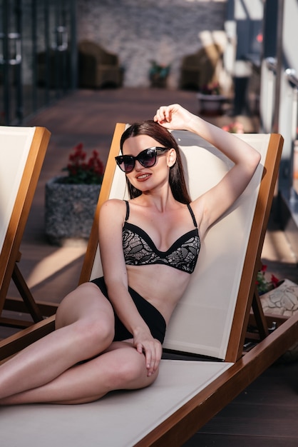 fille sur la terrasse dans une serviette de bain après la douche regarde le coucher de soleil dans les montagnes.