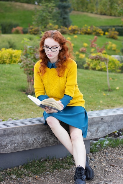 Fille De Tête De Lecture Assise Dans Un Parc Avec Un Livre